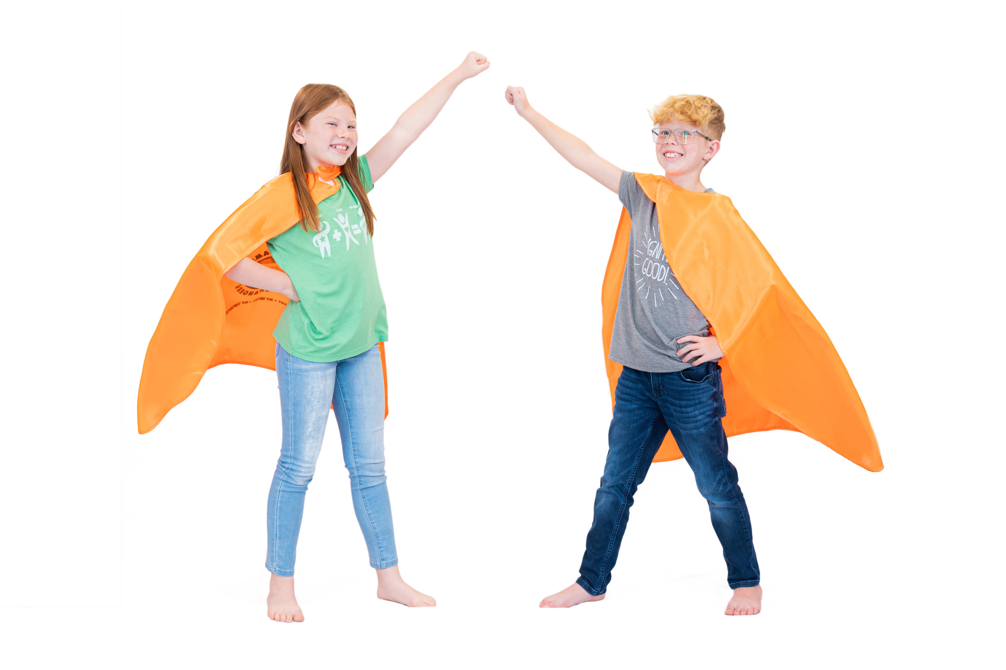 Two children wearing orange superhero capes on a white background