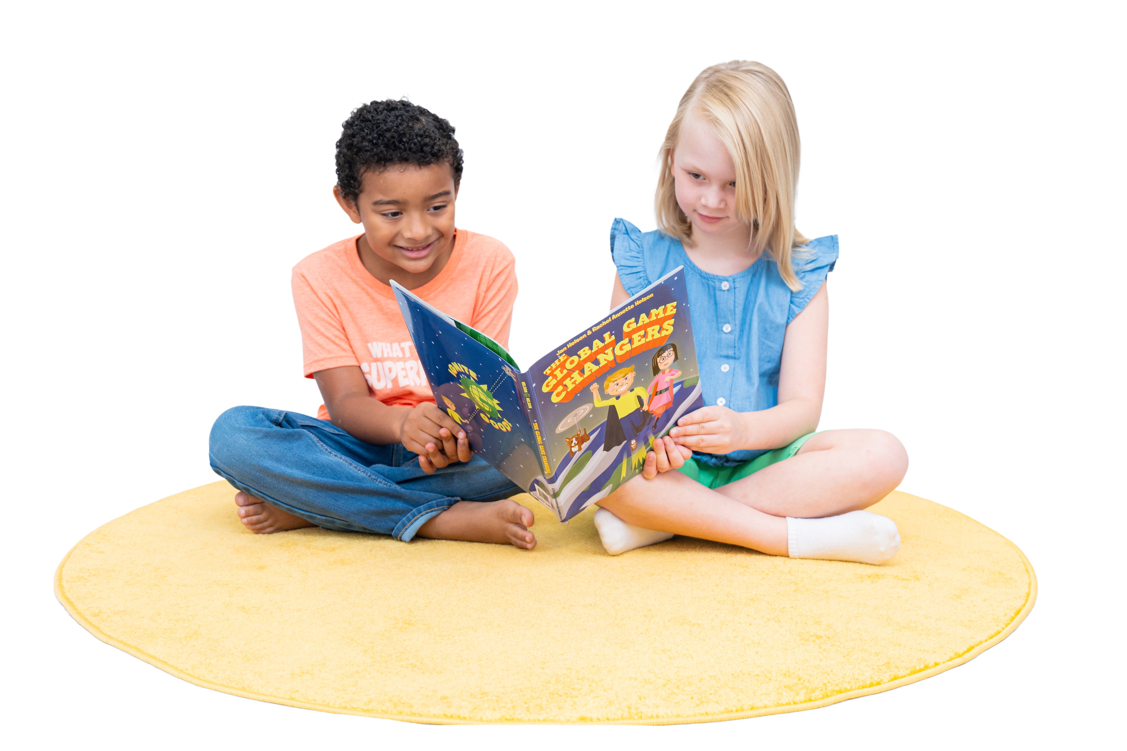 Two children sitting on a yellow mat, reading the Global Game Changers book together.