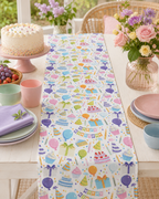 Table setting with a colorful table runner featuring custom printed birthday-themed designs, including cakes, balloons, and presents.