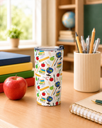 Tumbler with a custom printed teacher-themed design on a desk with books, apple, and stationery.