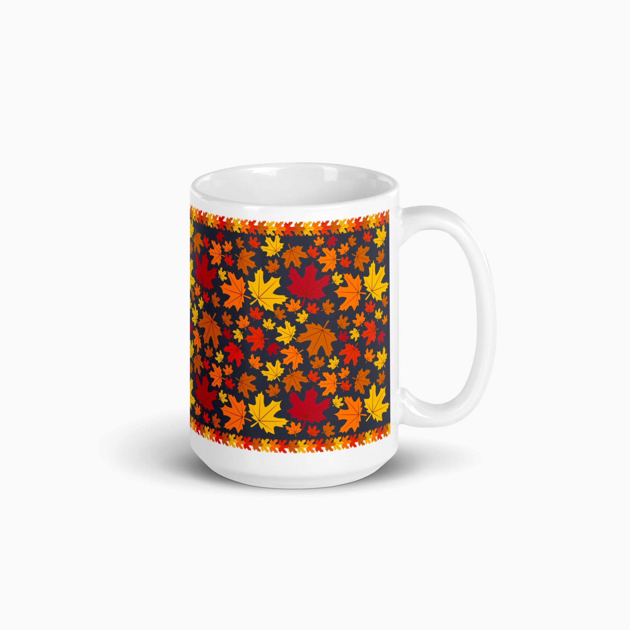 A white ceramic mug with a colorful autumn pattern, featuring red, orange, and yellow maple leaves on a dark background with decorative leaf borders photographed against a light-grey studio backdrop.