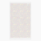 The white back side of a rectangular fabric kitchen towel featuring an all-over autumn maple leaf pattern in red, orange, yellow, and brown on a dark charcoal background, shown flat against a light gray backdrop.
