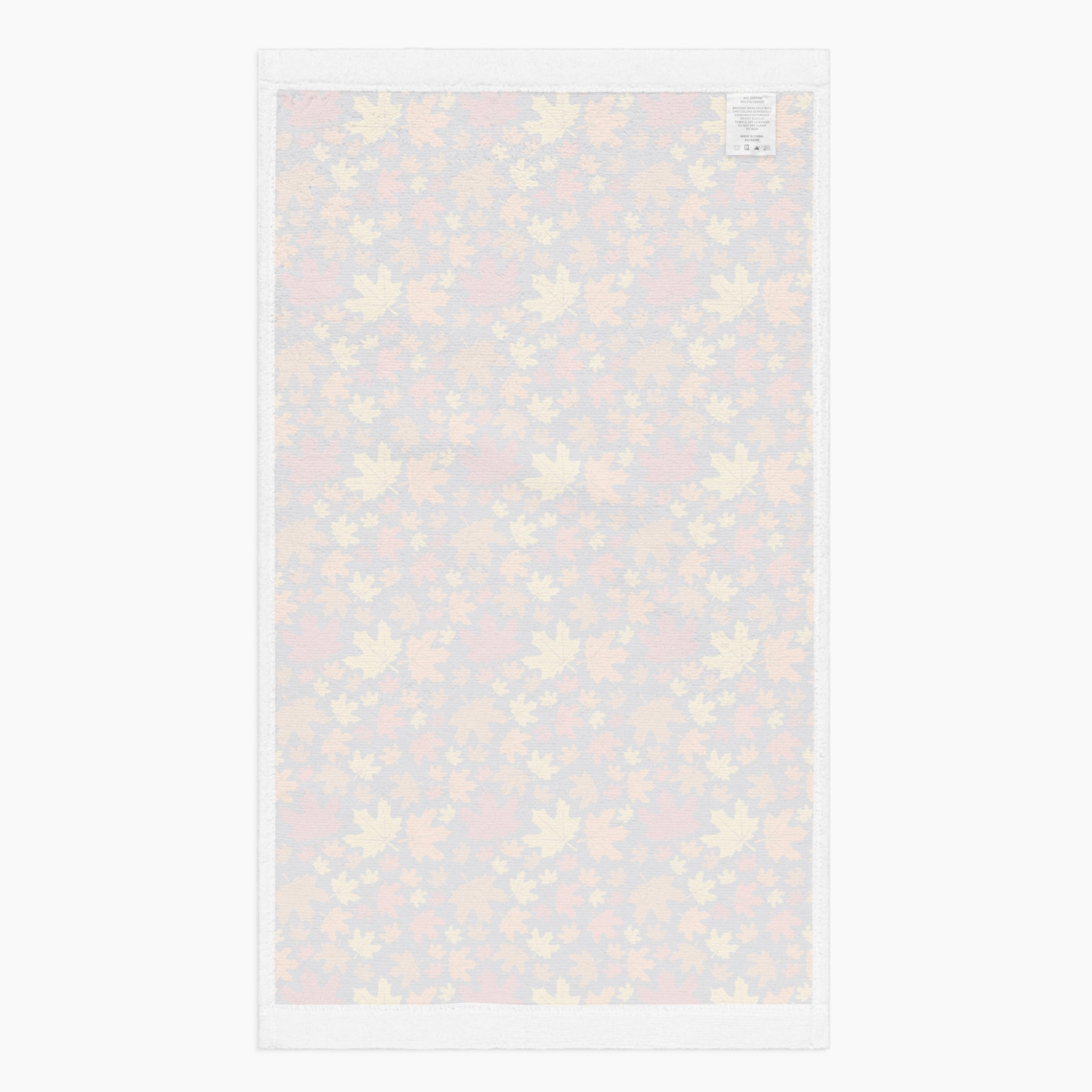 The white back side of a rectangular fabric kitchen towel featuring an all-over autumn maple leaf pattern in red, orange, yellow, and brown on a dark charcoal background, shown flat against a light gray backdrop.