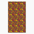 A rectangular fabric kitchen towel featuring an all-over autumn maple leaf pattern in red, orange, yellow, and brown on a dark charcoal background, shown flat against a light gray backdrop.