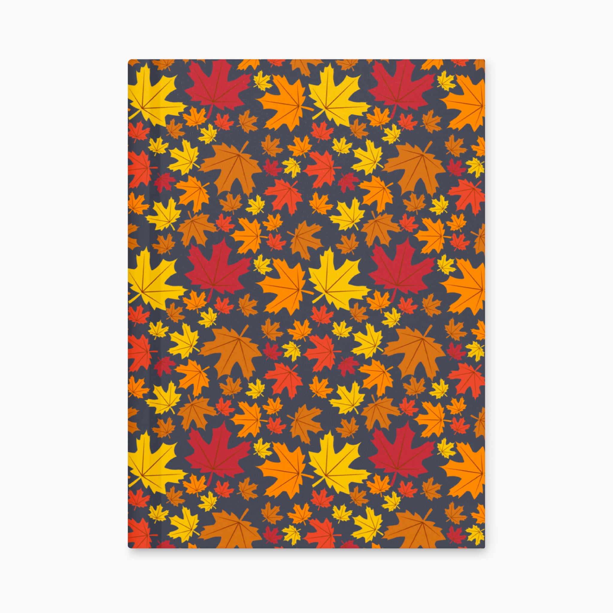 A notebook with a dark charcoal cover decorated with a dense pattern of colorful autumn maple leaves in red, orange, yellow, and brown, laying closed and flat against a light gray background.
