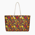 A tote bag with a dense autumn maple leaf pattern in red, orange, yellow, and brown on a dark charcoal background, featuring  white handles.