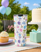 Tumbler with birthday-themed design on a table outdoors with cake and balloons.