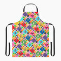 The front of a chef's apron with black straps with an all-over custom print pattern featuring a Halloween-themed diamond pattern with pumpkins, ghosts, bats, a skeleton, and cartoon kids in costumes, shown on a light gray background.