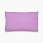 The back of a rectangular lavender colored throw pillow with a small black printed logo at the bottom center, displayed on a clean light grey background.