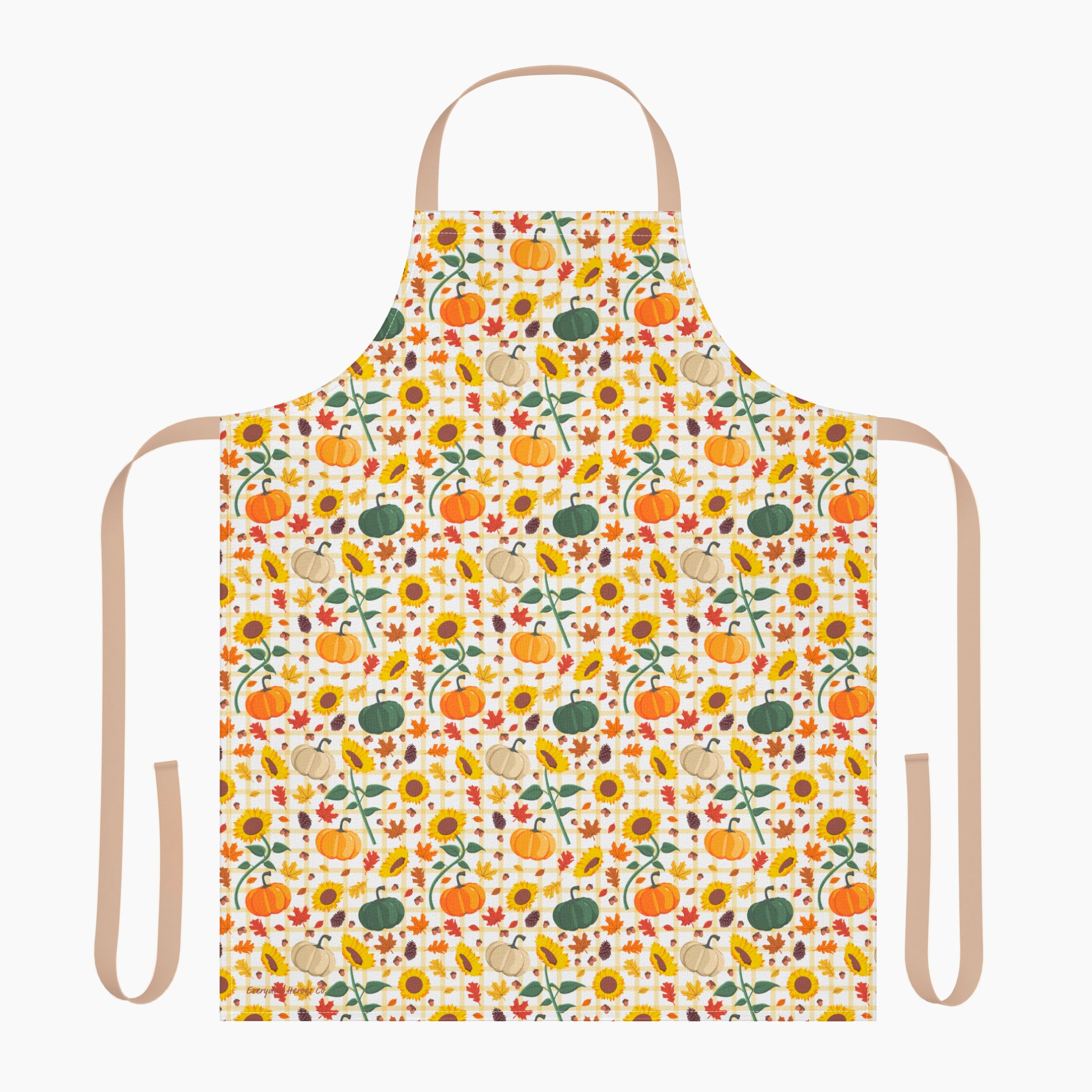 A white apron with a beige neck loop and waist ties, featuring an all-over autumn pattern of pumpkins, sunflowers, gourds, and fall leaves.