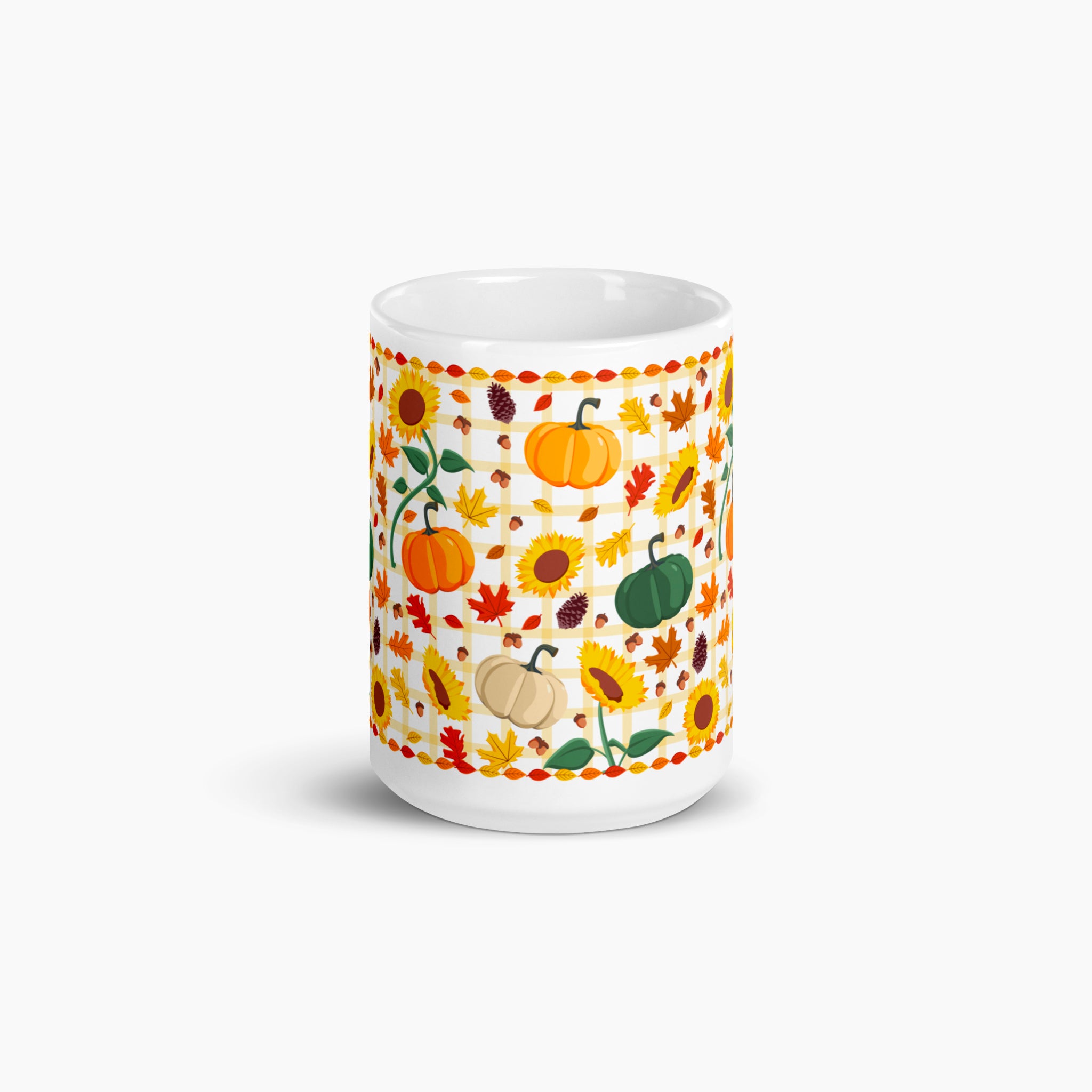 A white ceramic mug featuring a colorful autumn-themed pattern with pumpkins, sunflowers, maple leaves, and acorns, shown on a light gray background.