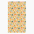 A dish towel featuring a repeating autumn pattern of pumpkins, sunflowers, gourds, acorns, and leaves on a light-grey studio backdrop.