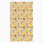 A dish towel featuring a repeating autumn pattern of pumpkins, sunflowers, gourds, acorns, and leaves on a light-grey studio backdrop.