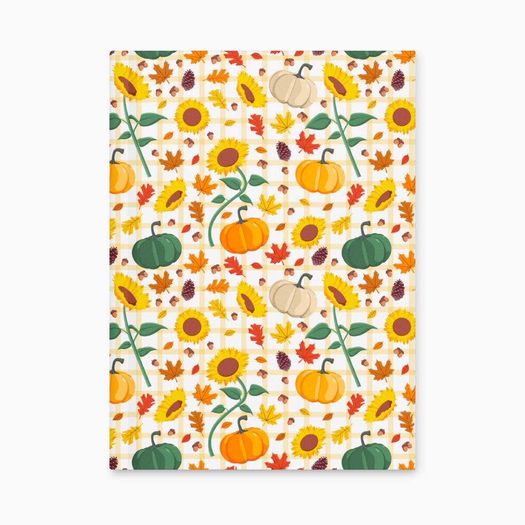 Front cover of a hardcover journal featuring a colorful autumn pattern of sunflowers, pumpkins, maple leaves, pinecones, and gingham checkered details on a light-grey background.