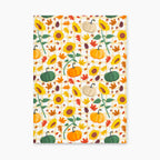 Front cover of a hardcover journal featuring a colorful autumn pattern of sunflowers, pumpkins, maple leaves, pinecones, and gingham checkered details on a light-grey background.