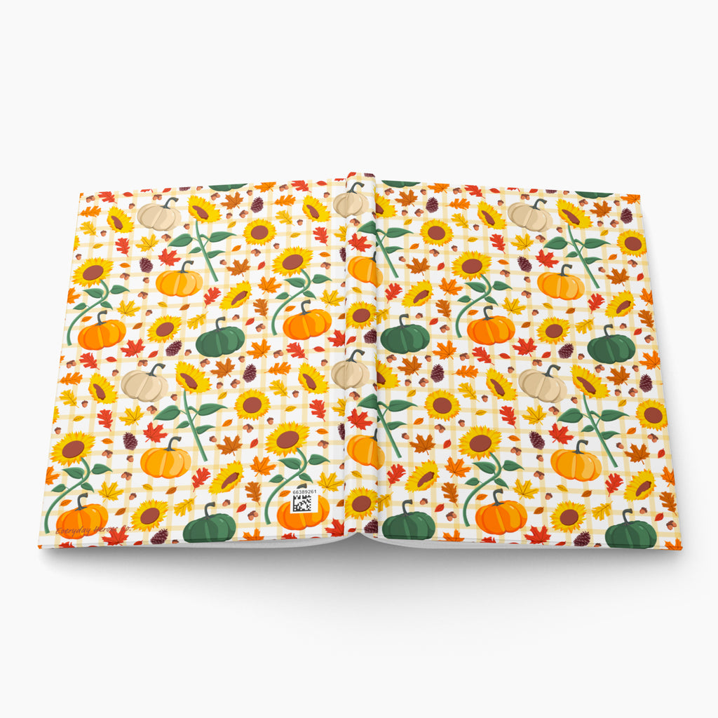Front and back cover of a hardcover journal featuring a colorful autumn pattern of pumpkins, sunflowers, and leaves on a white background, photographed on a light gray background.