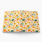 Front and back cover of a hardcover journal featuring a colorful autumn pattern of pumpkins, sunflowers, and leaves on a white background, photographed on a light gray background.