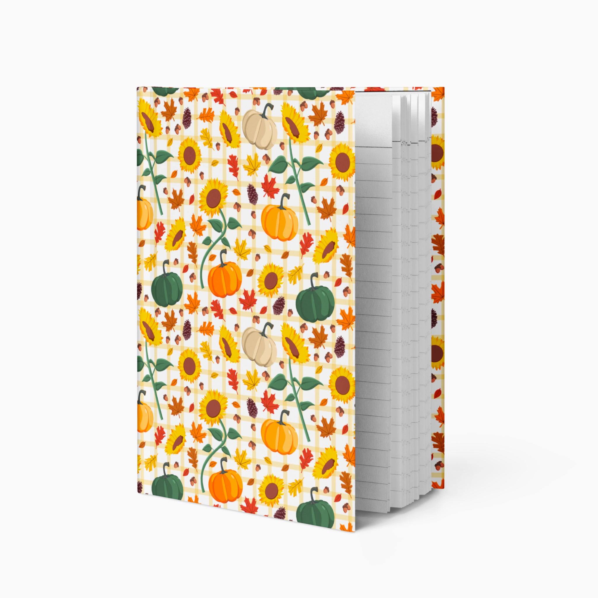 A hardcover notebook with a white cover decorated with a colorful autumn pattern of pumpkins, sunflowers, and leaves, standing upright on a light gray background.