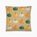 A square throw pillow featuring a repeating pattern of stylized pumpkins in orange, green, and cream on a warm beige background.