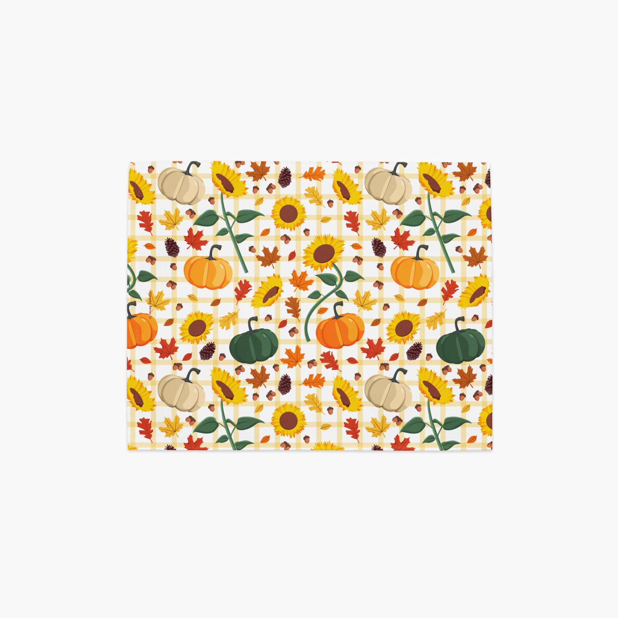 A rectangular placemat, featuring a repeating autumn pattern of pumpkins, sunflowers, maple leaves, and pinecones on a light-grey studio background.