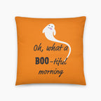 An orange square throw pillow featuring a white cartoon ghost and the text 'Oh, what a BOO-tiful morning' in black script, shown on a light gray background.