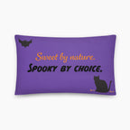 A rectangular purple throw pillow with a Halloween-themed design including a black bat and cat. The design features the text 'Sweet by nature. Spooky by Choice' staged on a light grey background.