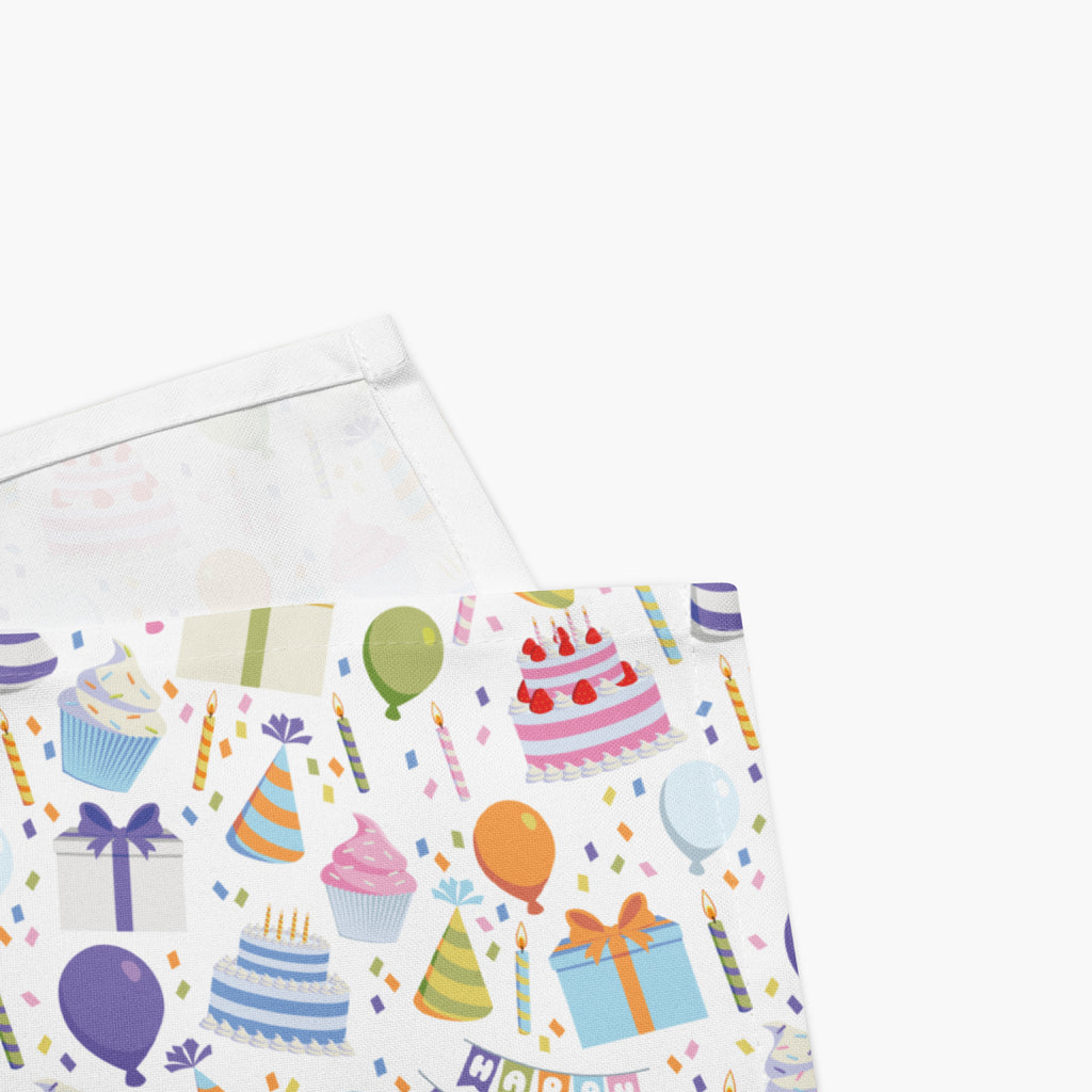 Close-up on corner of cloth napkins with a colorful pattern of birthday-themed illustrations on a white background.