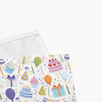 Close-up on corner of cloth napkins with a colorful pattern of birthday-themed illustrations on a white background.