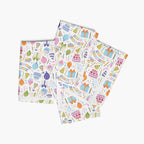 Four folded cloth napkins with a colorful pattern of birthday-themed illustrations on a white background.