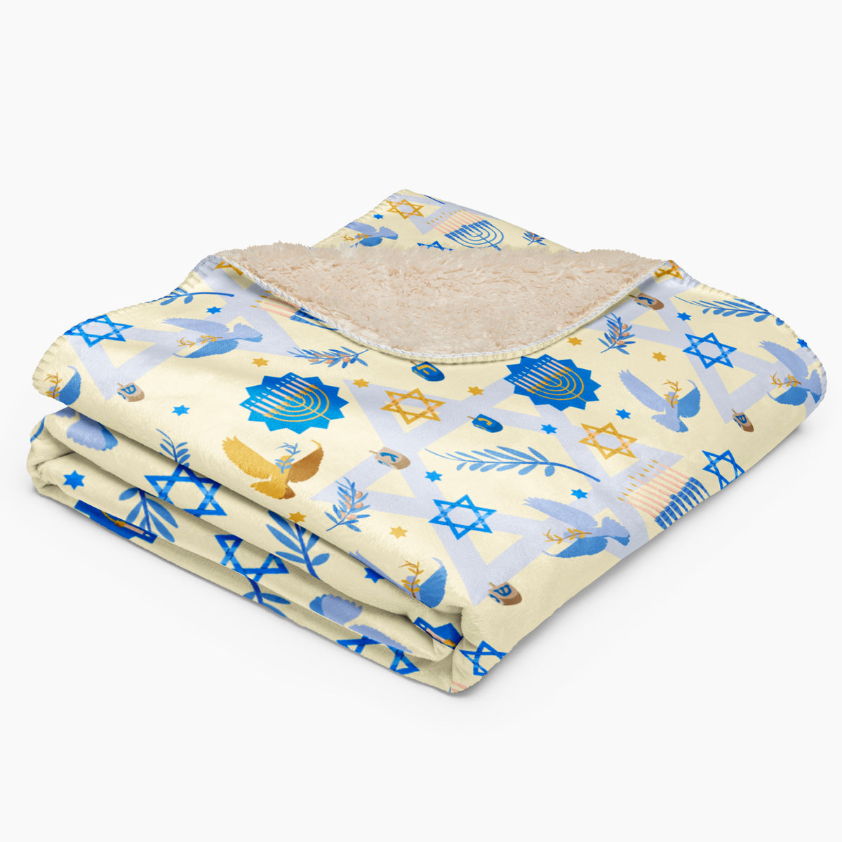 A folded blanket with a light beige sherpa lining and a printed fabric cover featuring blue and gold Star of David, Menorah, and dove motifs on a pale yellow background.