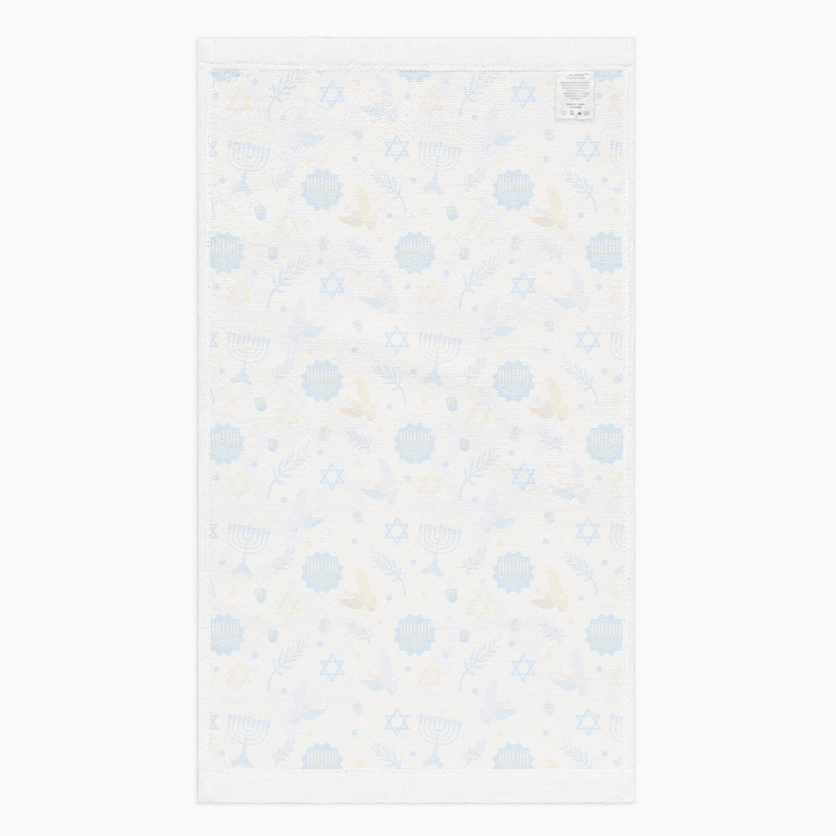 The white backside of a rectangular microfiber fabric hand towel with a repeating festive pattern featuring blue menorahs, blue Star of David motifs, blue circular medallions, gold stars, and small gold and blue doves shown flat against a light grey background