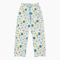 A pair of pajama pants with a festive Hanukkah holiday print featuring blue menorahs, Star of David symbols, dreidels, olive branches, and doves on a pale yellow background, complete with a blue drawstring waist.