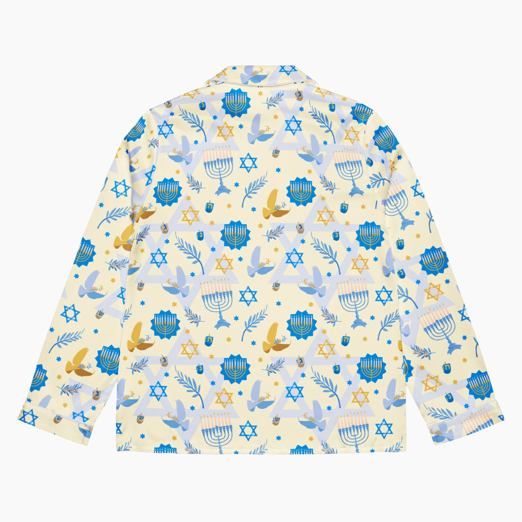 The back side of a long-sleeve button-up pajama shirt with a festive Hanukkah-themed print featuring blue menorahs, Star of David emblems, lulav and olive branches and gold and blue doves on a pale yellow background.