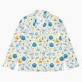 A long-sleeve button-up pajama shirt with a festive Hanukkah-themed print featuring blue menorahs, Star of David emblems, lulav and olive branches and gold and blue doves on a pale yellow background.