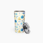 A stainless steel travel tumbler with a light cream background and a blue and gold Hanukkah-themed pattern, shown with its clear lid leaning against it on a white background.