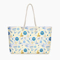 A cream-colored tote bag with a festive Jewish-themed pattern featuring blue menorahs, Star of David emblems, blue and gold doves on a light cream background, complete with two cream rope handles.