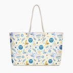 A cream-colored tote bag with a festive Jewish-themed pattern featuring blue menorahs, Star of David emblems, blue and gold doves on a light cream background, complete with two cream rope handles.
