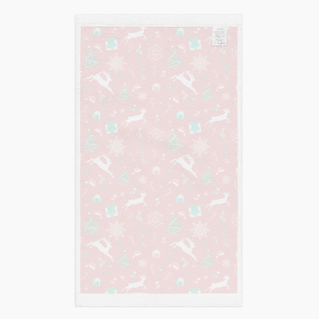 The white backing of a rectangular red holiday-themed patterned microfiber fabric hand towel featuring white reindeer, green Christmas trees, snowflakes, candy canes, and gift boxes, shown on a light gray background.