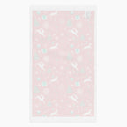 The white backing of a rectangular red holiday-themed patterned microfiber fabric hand towel featuring white reindeer, green Christmas trees, snowflakes, candy canes, and gift boxes, shown on a light gray background.