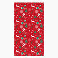 A rectangular red holiday-themed patterned microfiber fabric hand towel featuring white reindeer, green Christmas trees, snowflakes, candy canes, and gift boxes, shown on a light gray background.