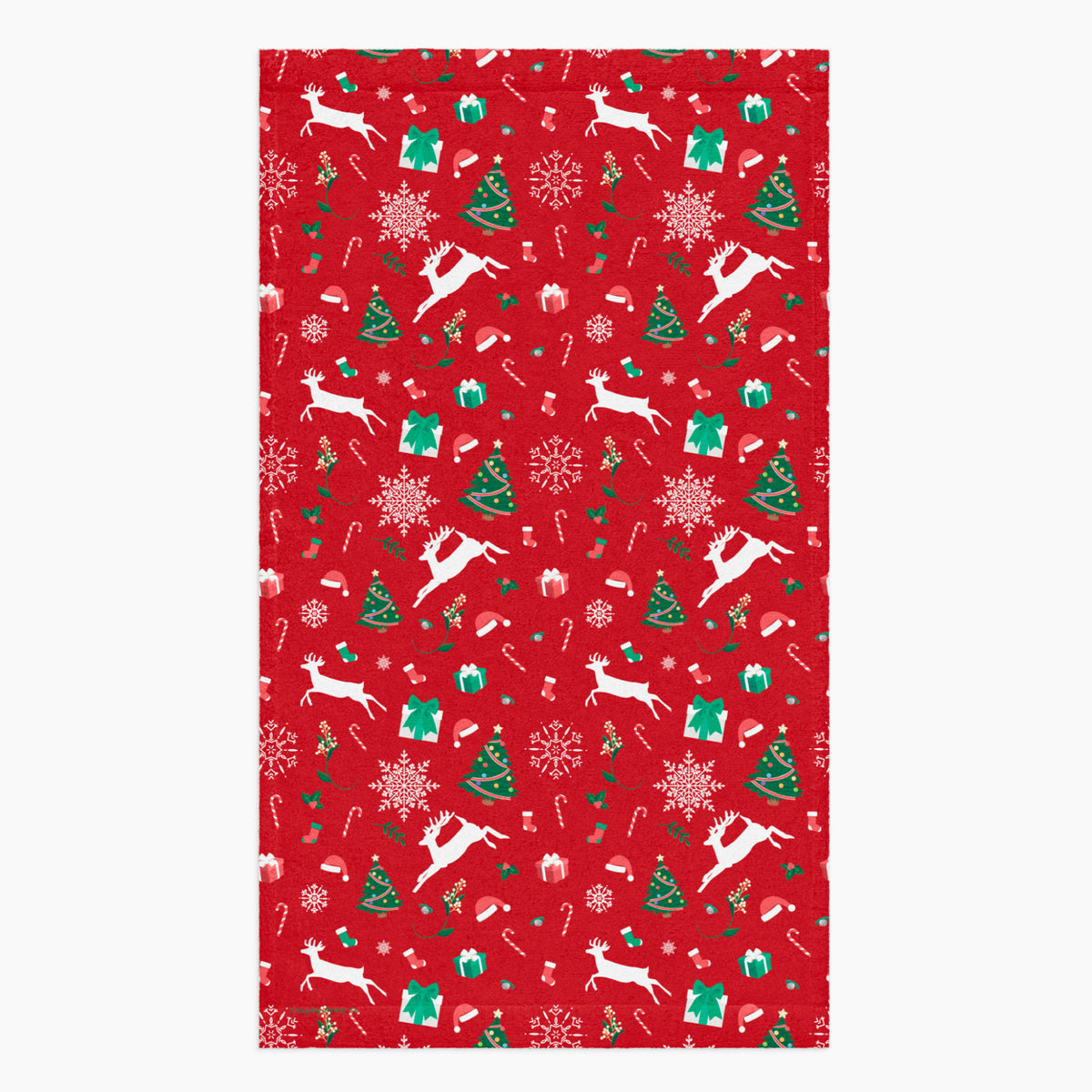 A rectangular red holiday-themed patterned microfiber fabric hand towel featuring white reindeer, green Christmas trees, snowflakes, candy canes, and gift boxes, shown on a light gray background.