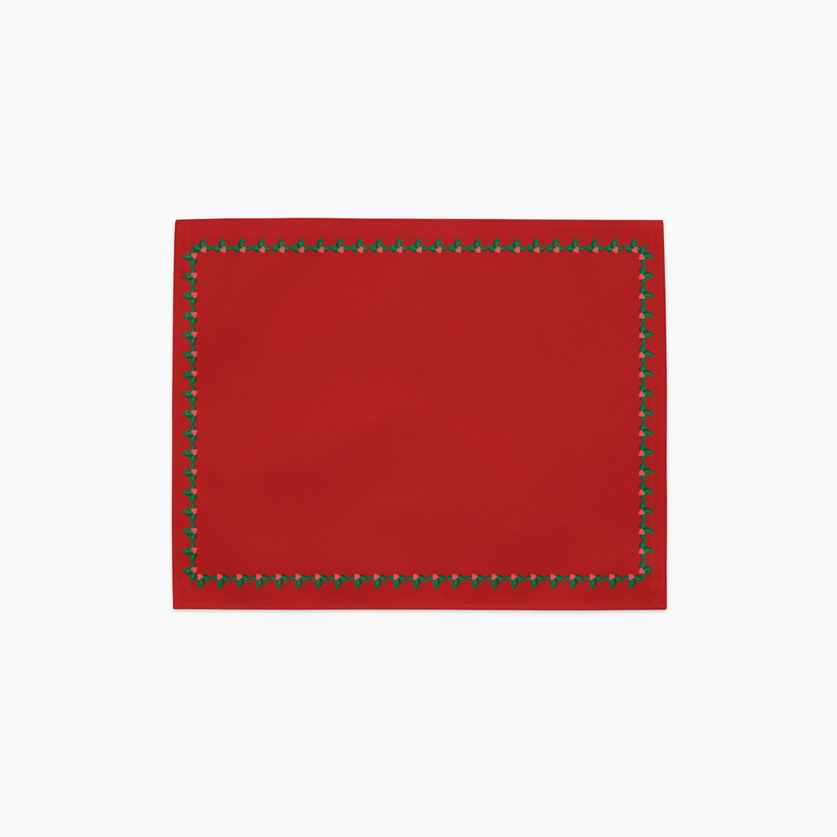 A rectangular red placemat with a decorative border of small green holly leaves and berries shown flat against a light gray background.