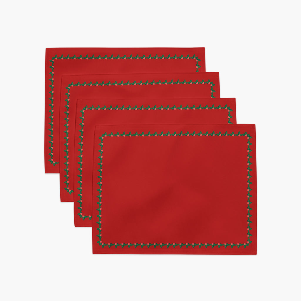 Four red rectangular with a decorative border of small green holly leaves and berries arranged in a staggered stack on a light gray background.