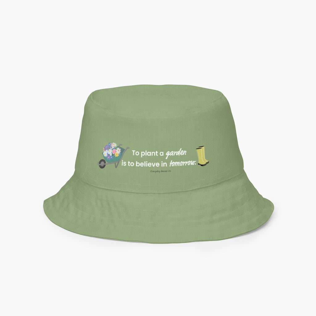 Reversible light green bucket hat with text 'To plant a garden is to believe in tomorrow.' and garden design on a white background