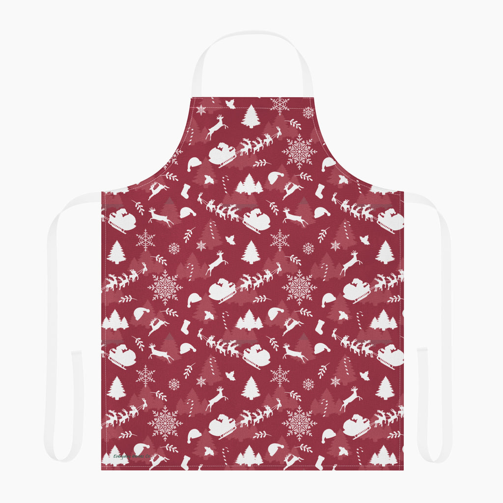 A deep red apron with a white winter holiday pattern featuring snowflakes, Christmas trees, reindeer, sleighs, and mountains, shown against a plain light grey background.