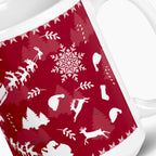 A close-up of a white ceramic mug featuring a festive deep red wraparound print with white holiday silhouettes, including snowflakes, trees, Santa hats, sleighs, and reindeer.