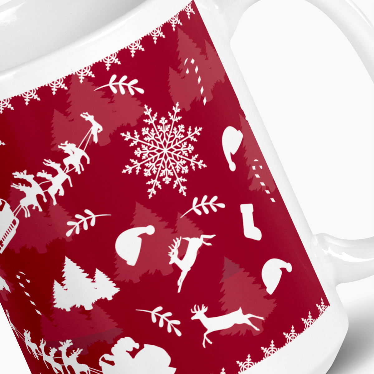 A close-up of a white ceramic mug featuring a festive deep red wraparound print with white holiday silhouettes, including snowflakes, trees, Santa hats, sleighs, and reindeer.