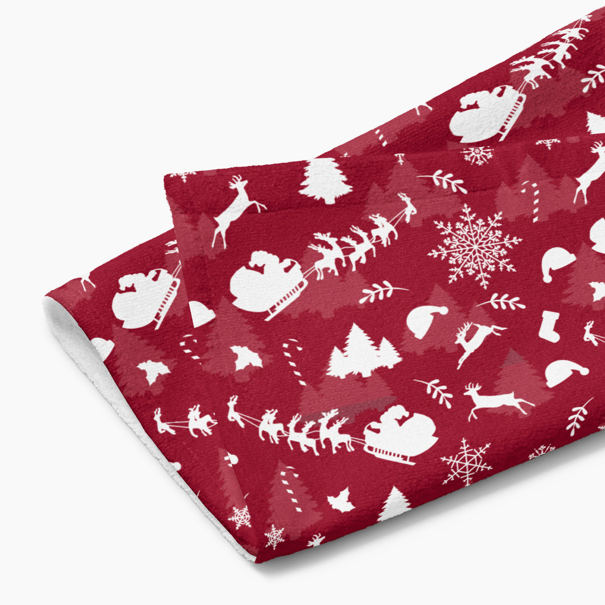 A folded deep red hand towel featuring a repeating white Christmas pattern with Santa Claus, sleighs, trees, snowflakes, and winter motifs, shown on a light gray background.
