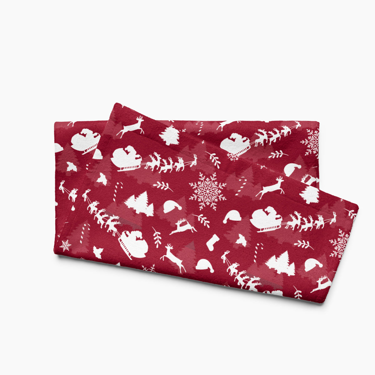 A folded deep red hand towel featuring a repeating white Christmas pattern with Santa Claus, sleighs, trees, snowflakes, and winter motifs, shown on a light gray background.