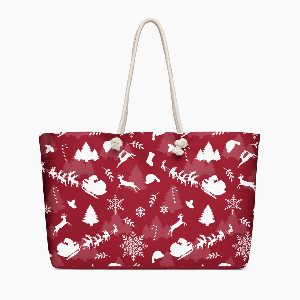 A deep red tote bag with a white Christmas-themed pattern featuring Santa Claus, reindeer, snowflakes, and trees, complete with two cream rope handles.